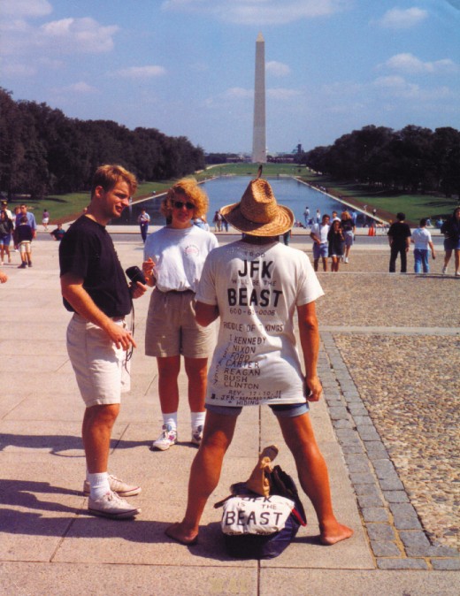 a "JFK is the Beast" protestor at the Washington Mall (with the pond and Washington Monument)